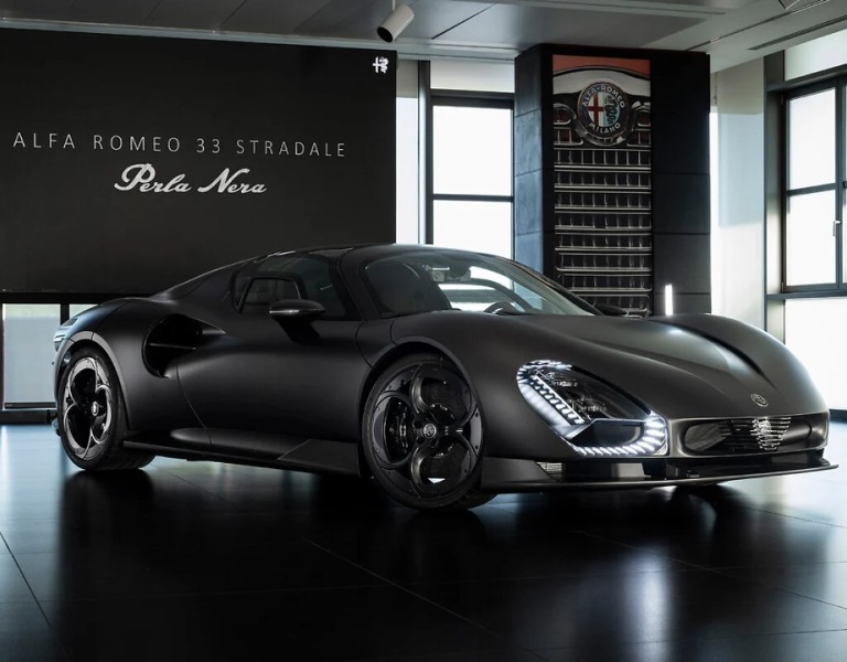 Alfa Romeo 33 Stradale Perla Nera en color negro, visto de frente en un  showroom, con faros LED encendidos. 